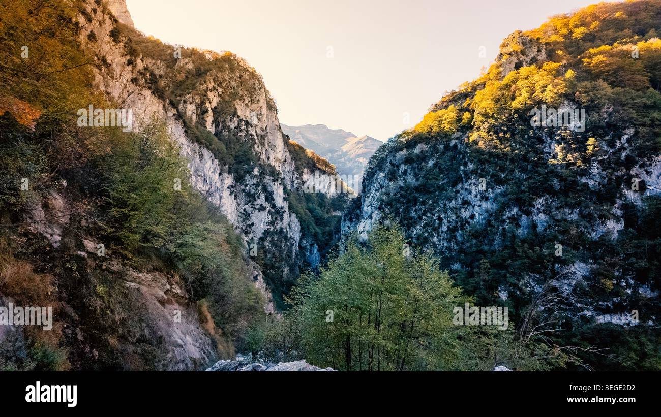 Vista della gola dell'Infernaccio con ripide scogliere calcaree e alberi color autunno sotto un cielo limpido Montefortino, Marche, Italia. Foto Stock