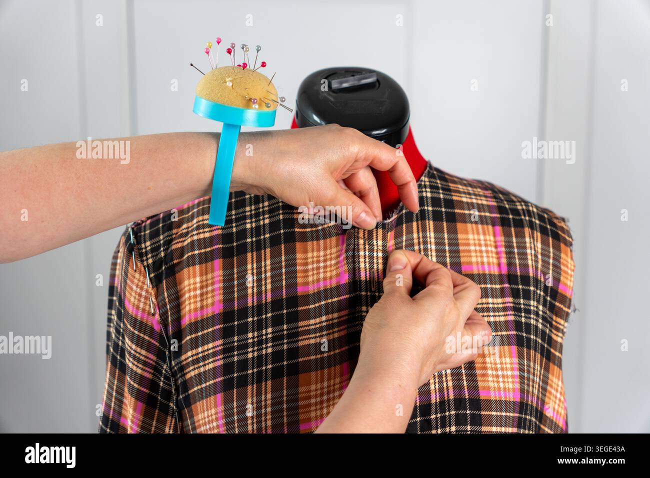 Donna che firma e fissa il tessuto su un manichino sartoriale con spille da cucire durante il montaggio e il processo di creazione della sartoria. Lavori di sartoria dettagliati con tessuto ma Foto Stock
