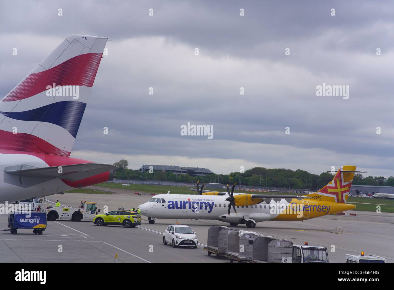 British Airways e Aurigny Aircraft sulla trafficata asfalto dell'aeroporto di Gatwick, Inghilterra Foto Stock