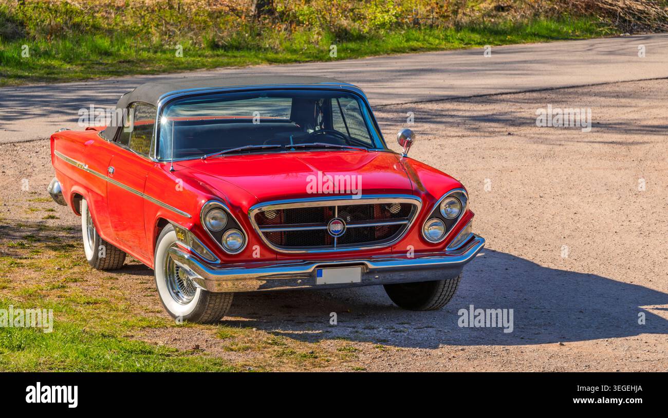 Chrysler 300 cabriolet d'epoca rossa parcheggiata da una strada rurale al sole primaverile, Kinnekulle, Västra Götaland, Svezia. Foto Stock