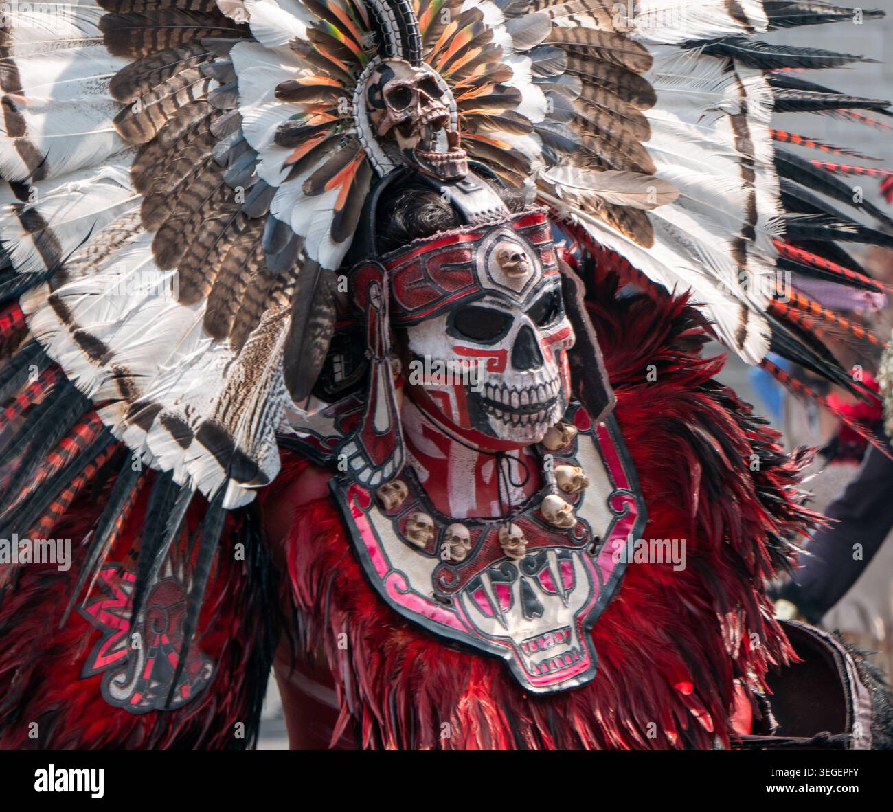 Ballerina tradizionale azteca che indossa una maschera dettagliata del cranio e un grande copricapo di piume durante una celebrazione culturale messicana Foto Stock