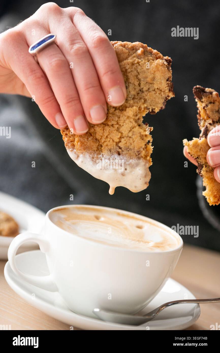 Gusta un biscotto caldo al cioccolato con una tazza di caffè fumante Foto Stock