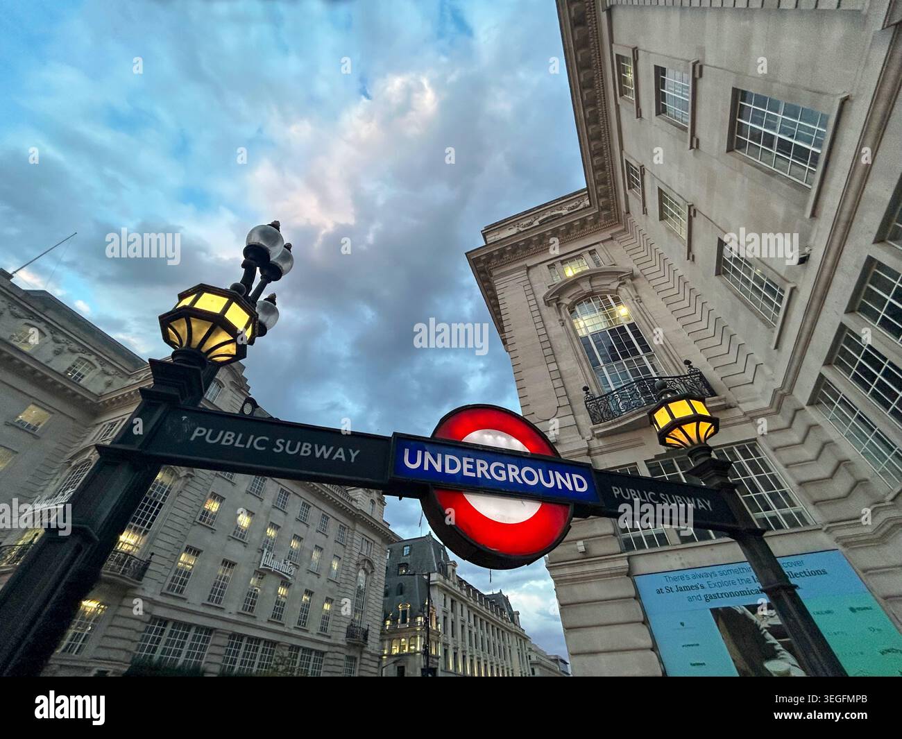 Londra, Regno Unito - 15 maggio 2026: L'iconico cartello rosso e blu della metropolitana di Londra e le tradizionali lanterne al crepuscolo, incorniciate Foto Stock