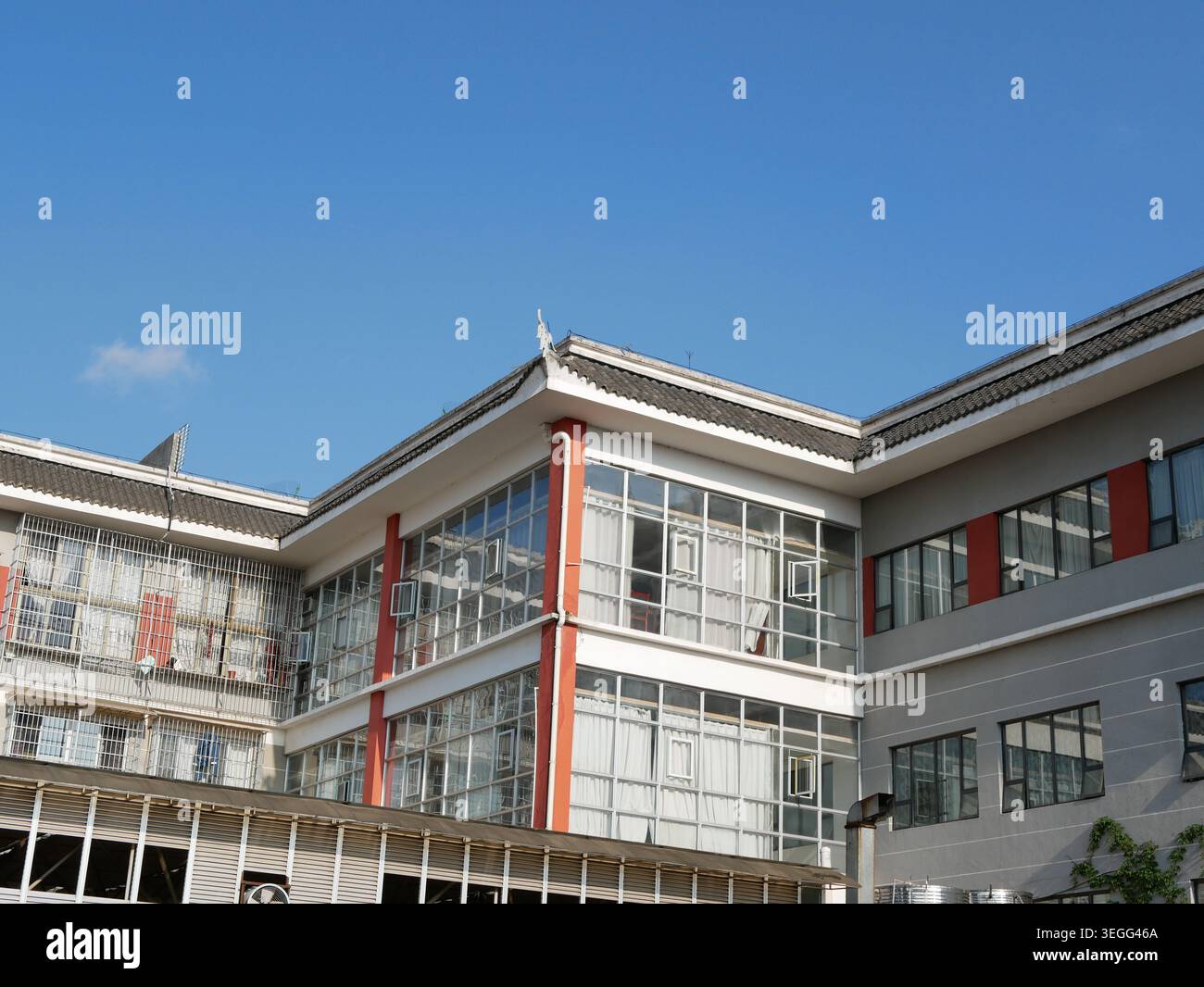 Moderno edificio alberghiero con dettagli architettonici tradizionali cinesi sul tetto e serrature di sicurezza sotto il cielo azzurro Foto Stock