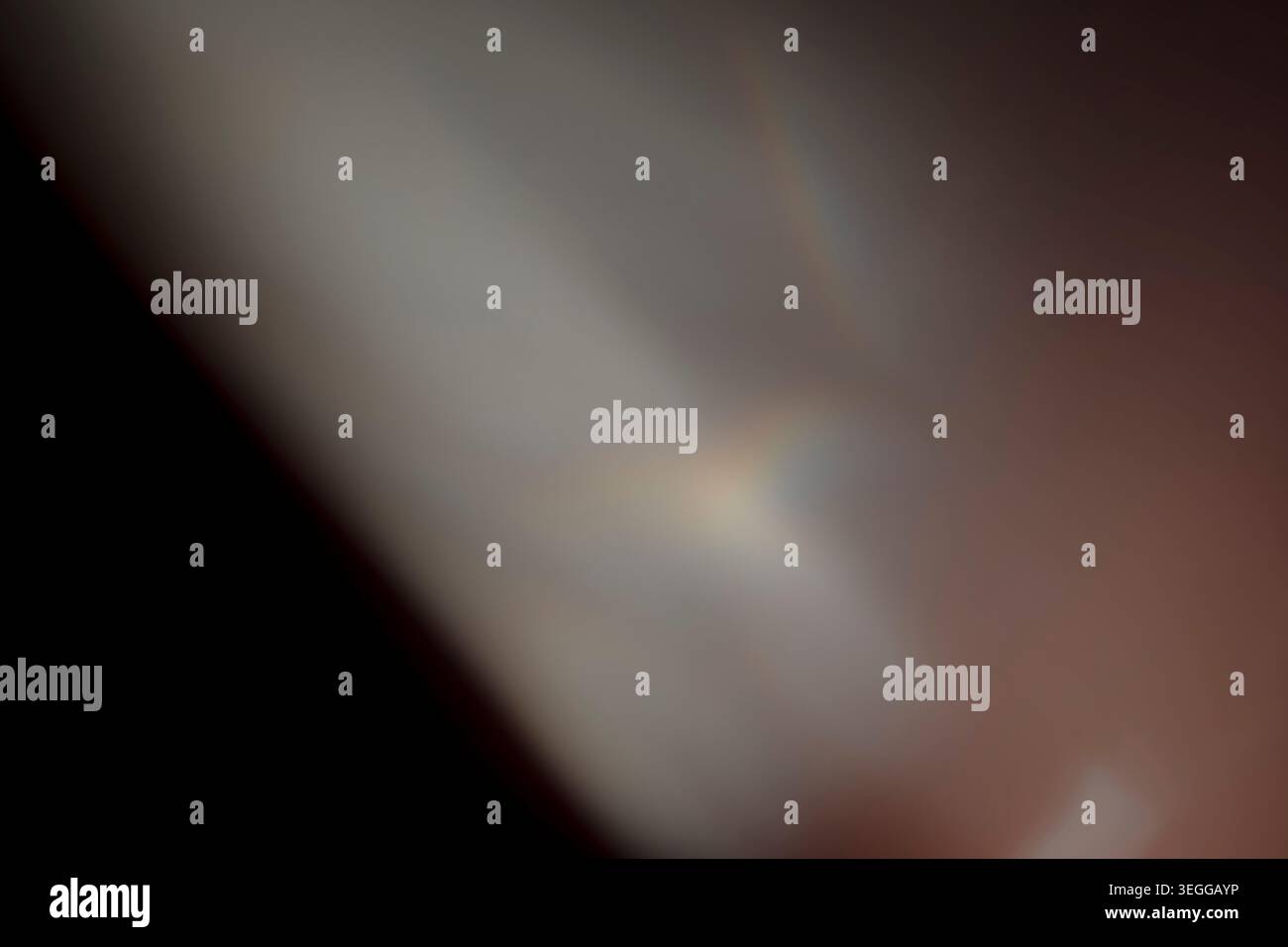 Sovrapposizione astratta di perdite di luce sfocata con luci calde soffuse e sottili effetti arcobaleno prismatici su uno sfondo scuro Foto Stock