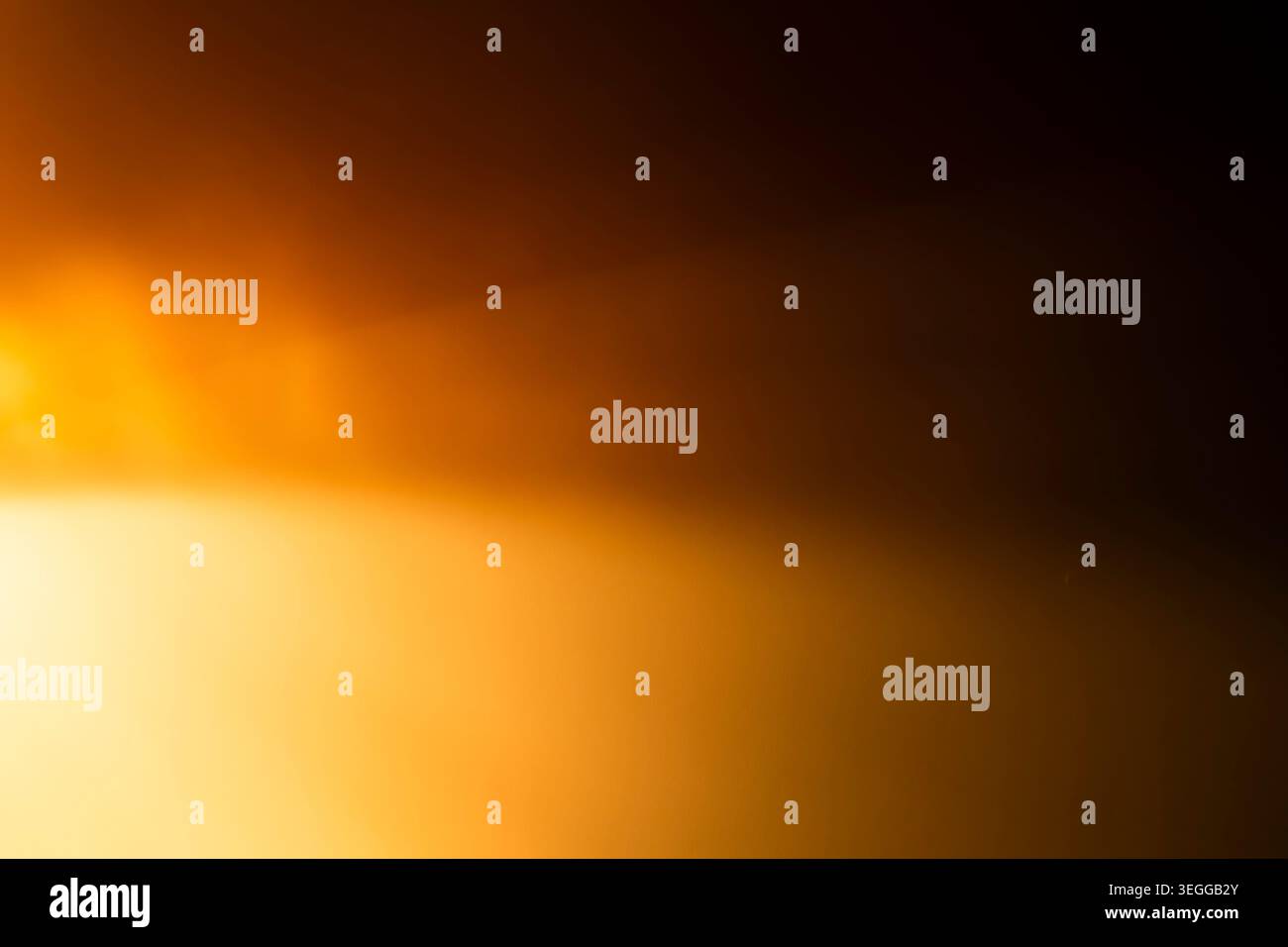 La luce calda arancione e dorata si sovrappongono su sfondo scuro Foto Stock