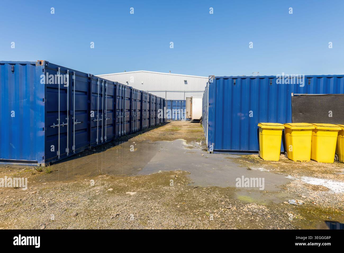 File di contenitori di stoccaggio in metallo blu disposti all'aperto in un'area commerciale di stoccaggio autonomo o industriale sotto cieli azzurri Foto Stock