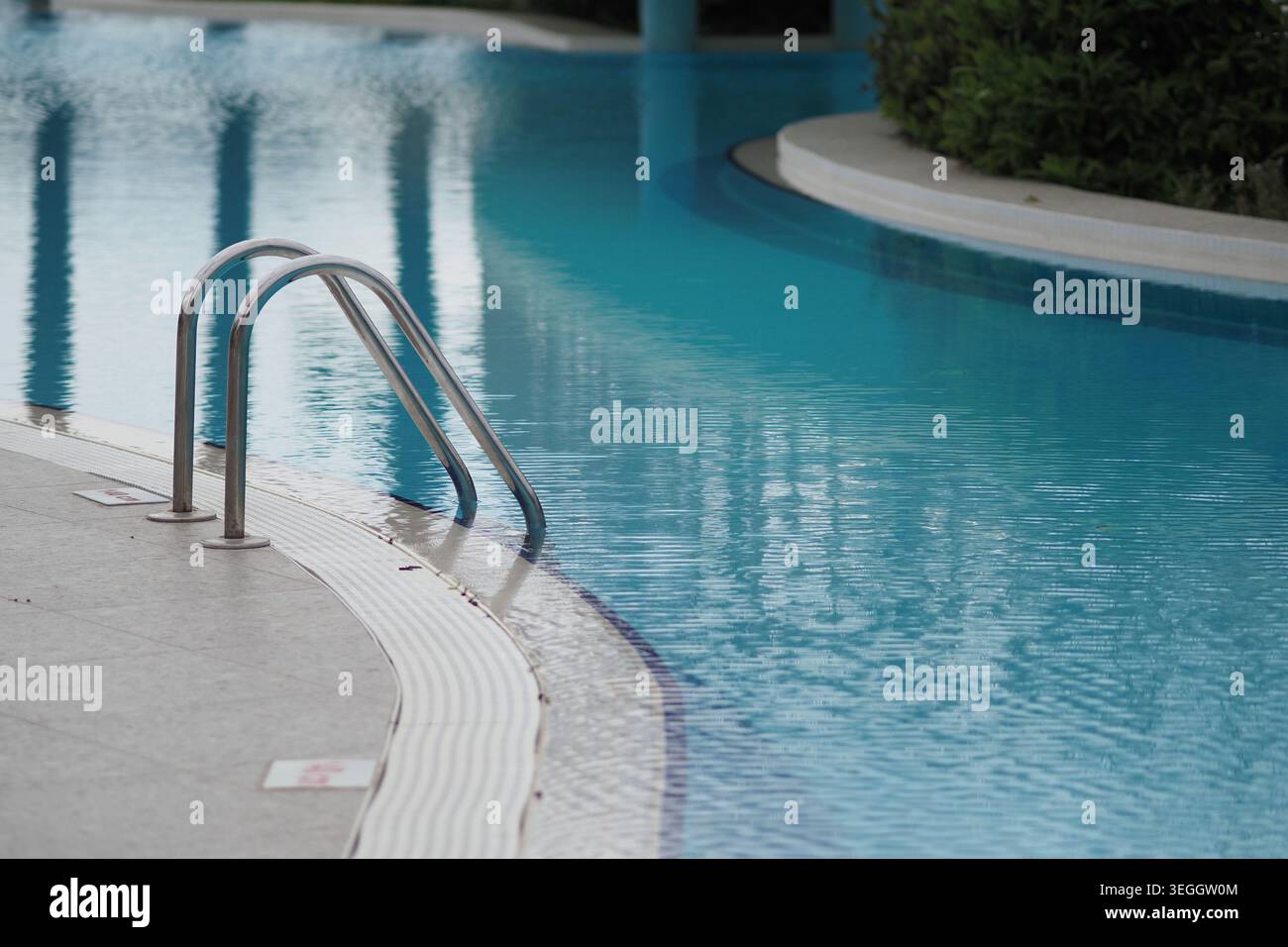 L'acqua riflette la luce a bordo piscina con scala argentata Foto Stock