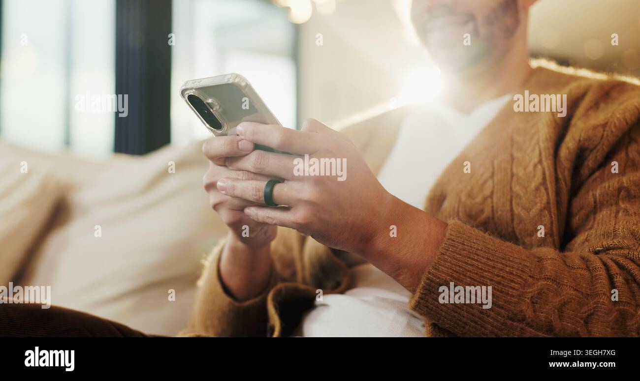 Telefono, mani e uomo a casa per messaggi di testo, incontri online e notifiche sui social media sul divano. App, mobile e persona in salotto per Foto Stock