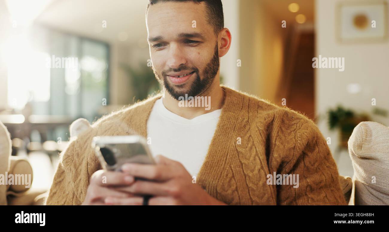Mobile, relax e uomo a casa per messaggi di testo, incontri online e notifiche sui social media sul divano. Sorridi, telefono e persona in salotto per Foto Stock
