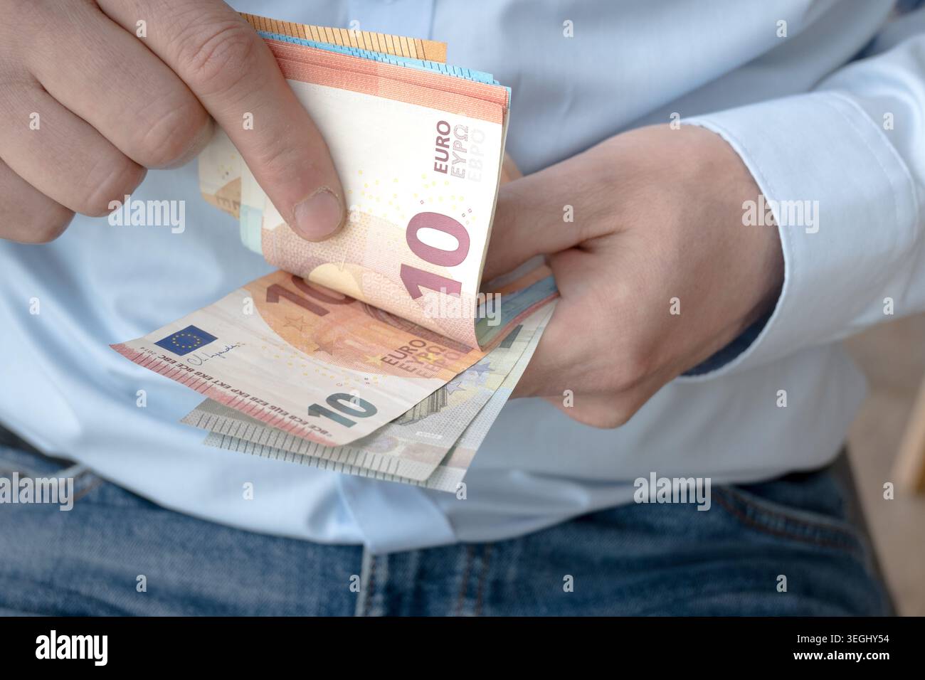 Un uomo d'affari con una camicia leggera tiene in mano i soldi europei. Foto Stock