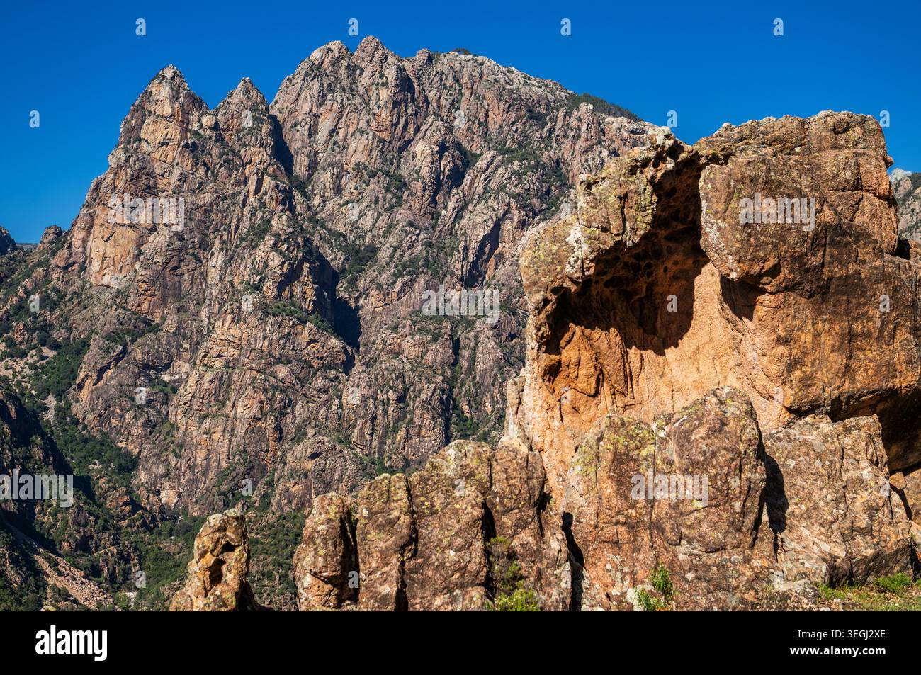 La gente esplora una catena montuosa in Corsica, Francia. Il cielo è blu e il sole splende luminoso. Le rocce robuste sono alte e presentano una forma unica Foto Stock