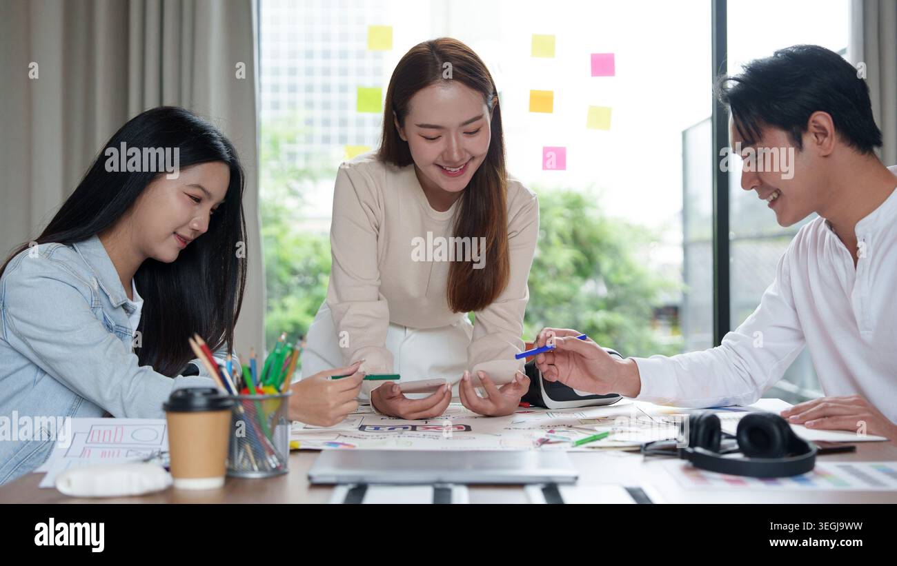 Designer asiatici dell'interfaccia utente utente che collaborano allo sviluppo di applicazioni mobili negli uffici moderni. Foto Stock