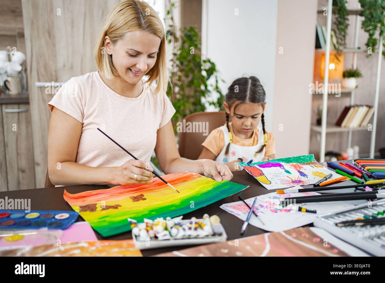 Madre e figlia si godono una sessione di pittura creativa a casa in uno spazio luminoso e accogliente Foto Stock