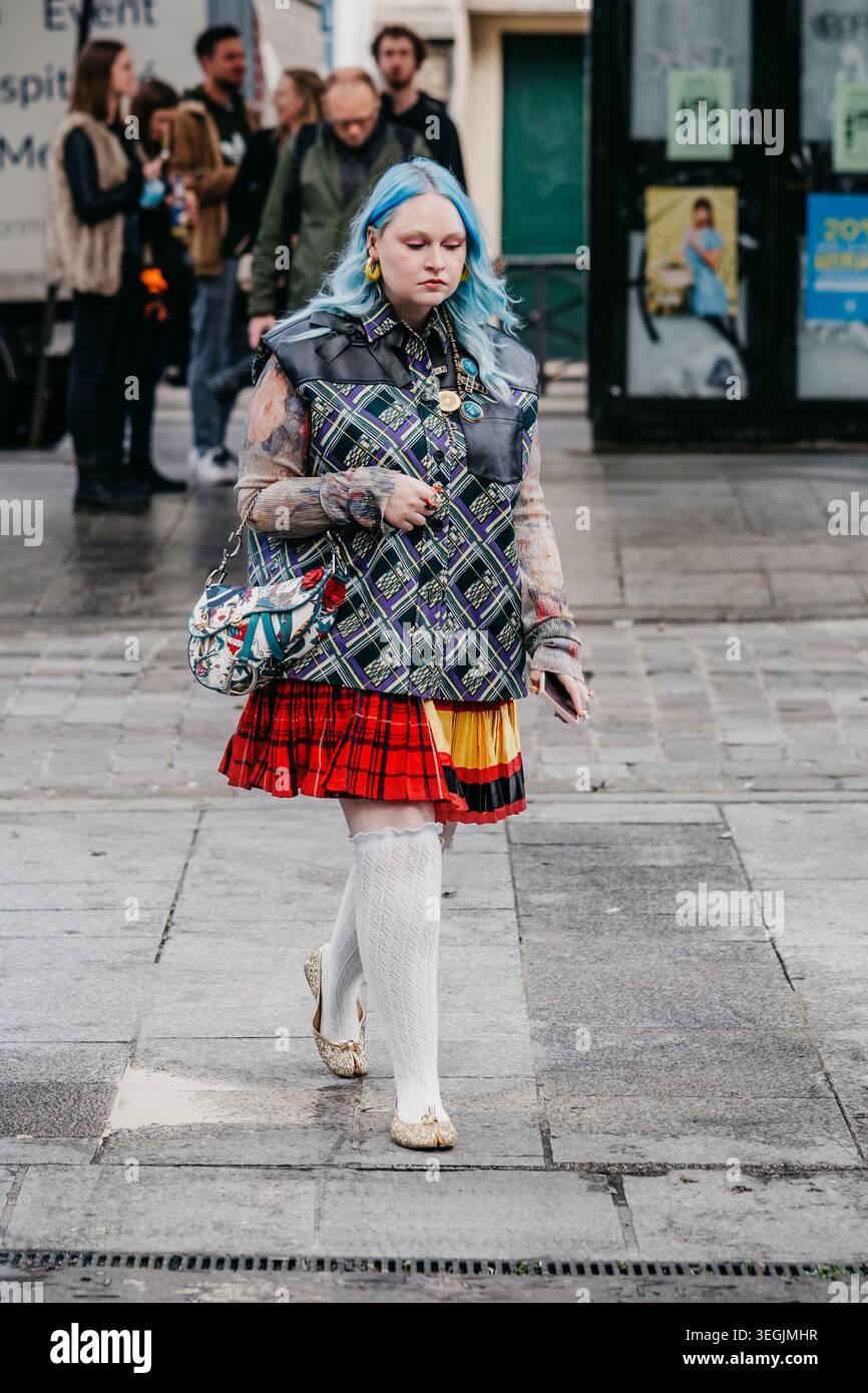 Parigi, Francia - 02.10.2021: Donna con capelli blu e stile eclettico Street fashion che indossa gonna a quadri, gilet a motivi geometrici, calze al ginocchio bianche e borsa Dior. Foto Stock