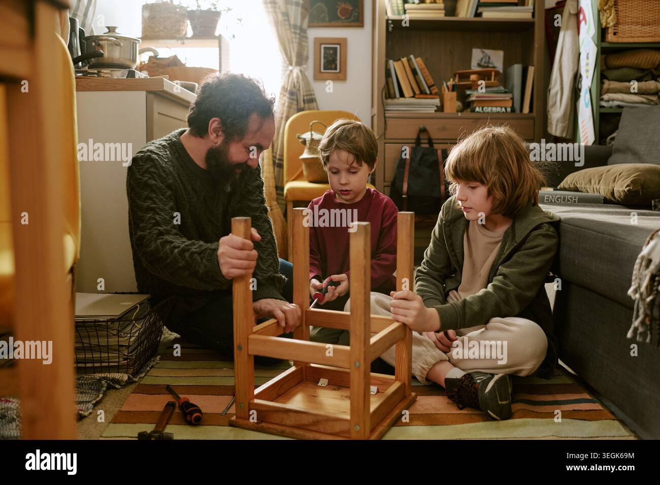 Padre con bambini che assemblano mobili durante budget Home Living Foto Stock