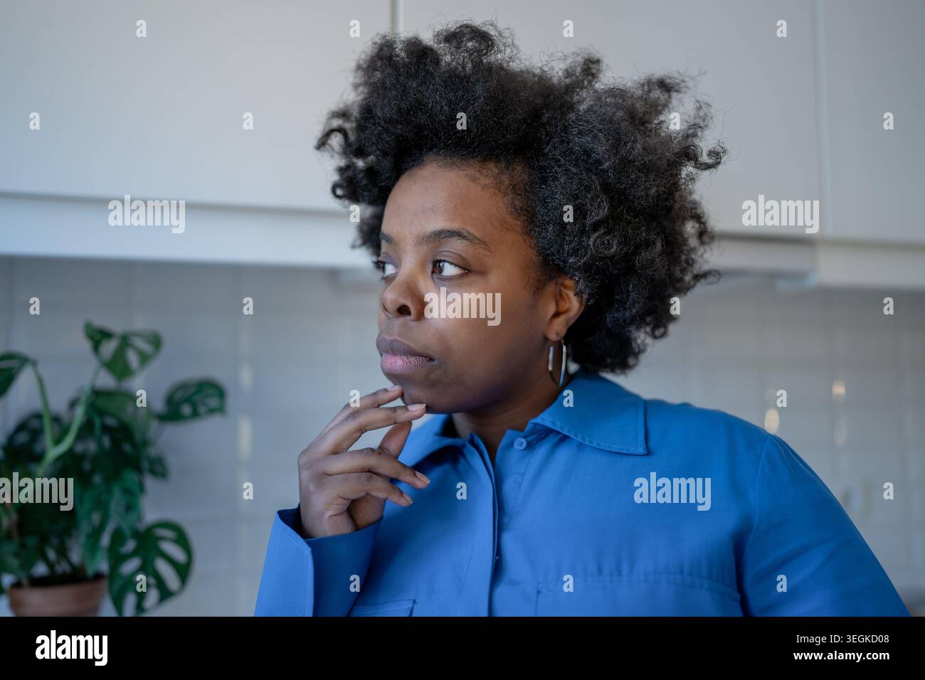 Donna nera premurosa che tocca il mento guardando da parte il processo decisionale, l'autoriflessione, il dialogo interiore. Foto Stock