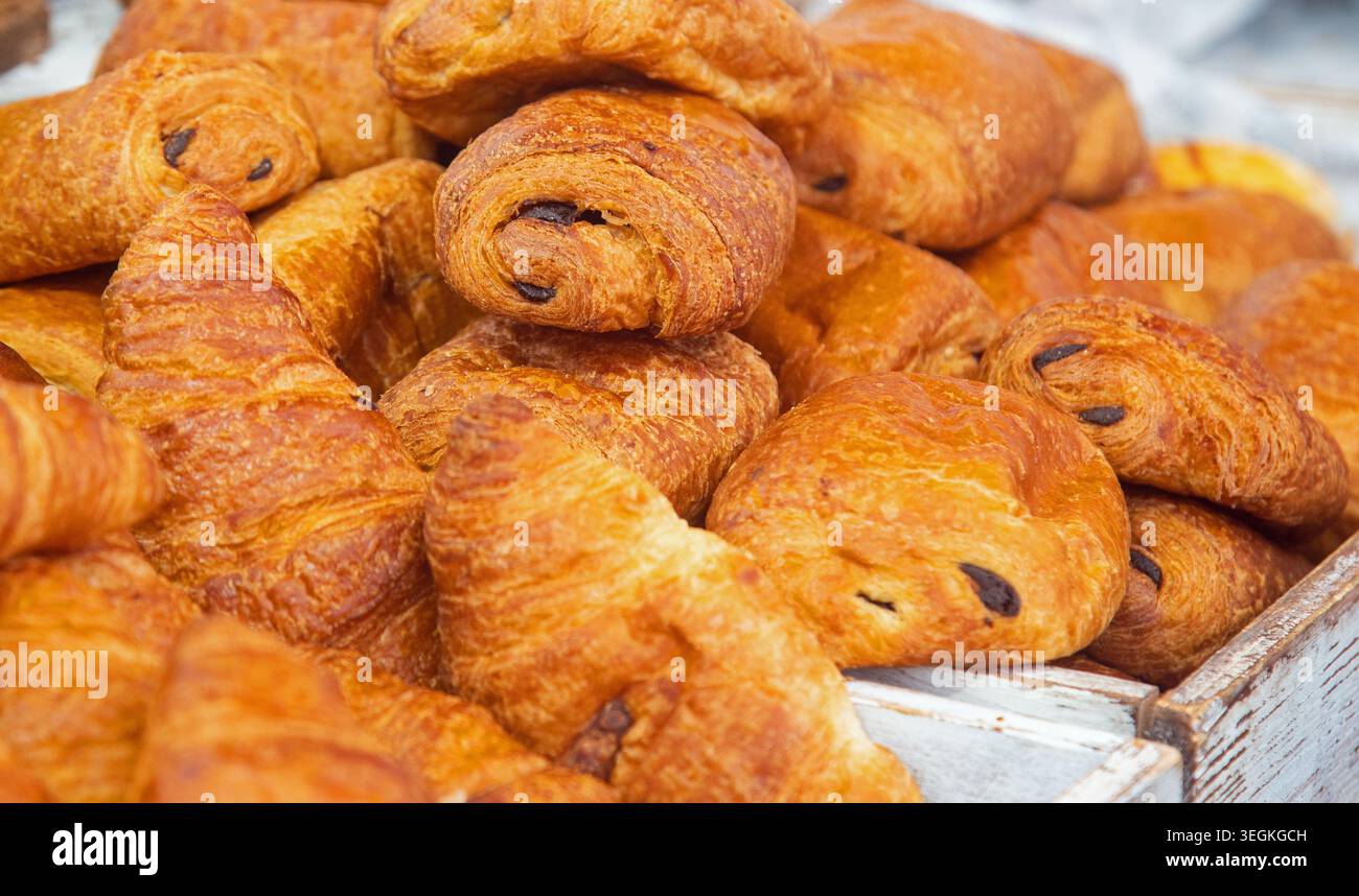 Cornwall, Inghilterra, giugno 2025, pasticcini francesi dorati Pain au chocolate attendono clienti affamati in un mercato Foto Stock
