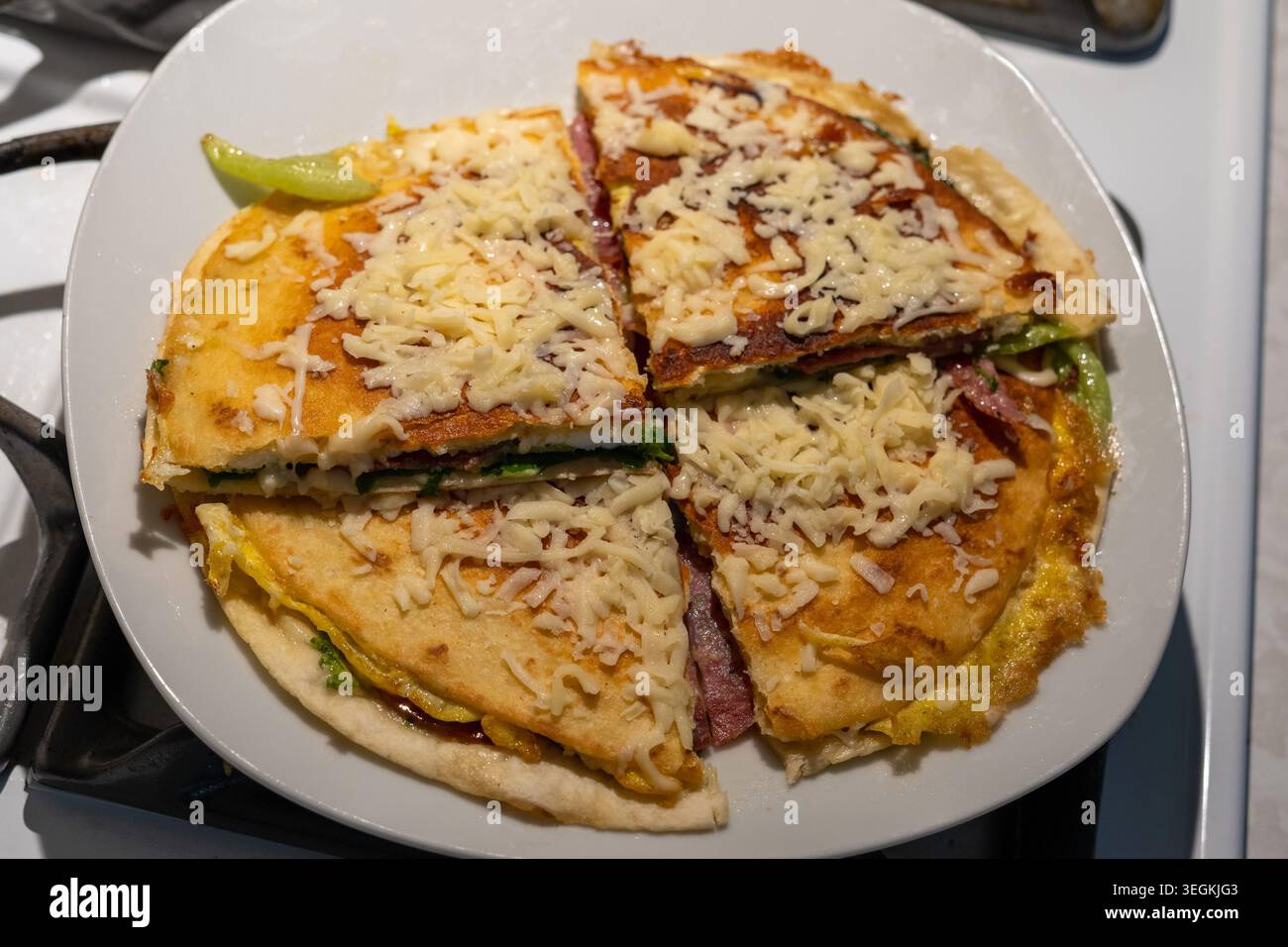 Una foto ravvicinata ad alto angolo di una tortilla fatta in casa tagliata in quattro quarti su un piatto di ceramica bianca. Il flatbr dorato-marrone croccante Foto Stock