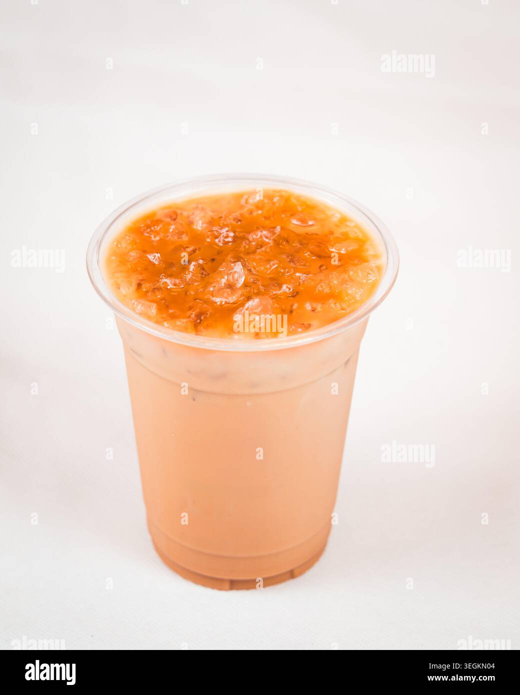 Tè al latte freddo con parte superiore in ghiaccio tritato in una tazza di plastica trasparente su sfondo bianco Foto Stock