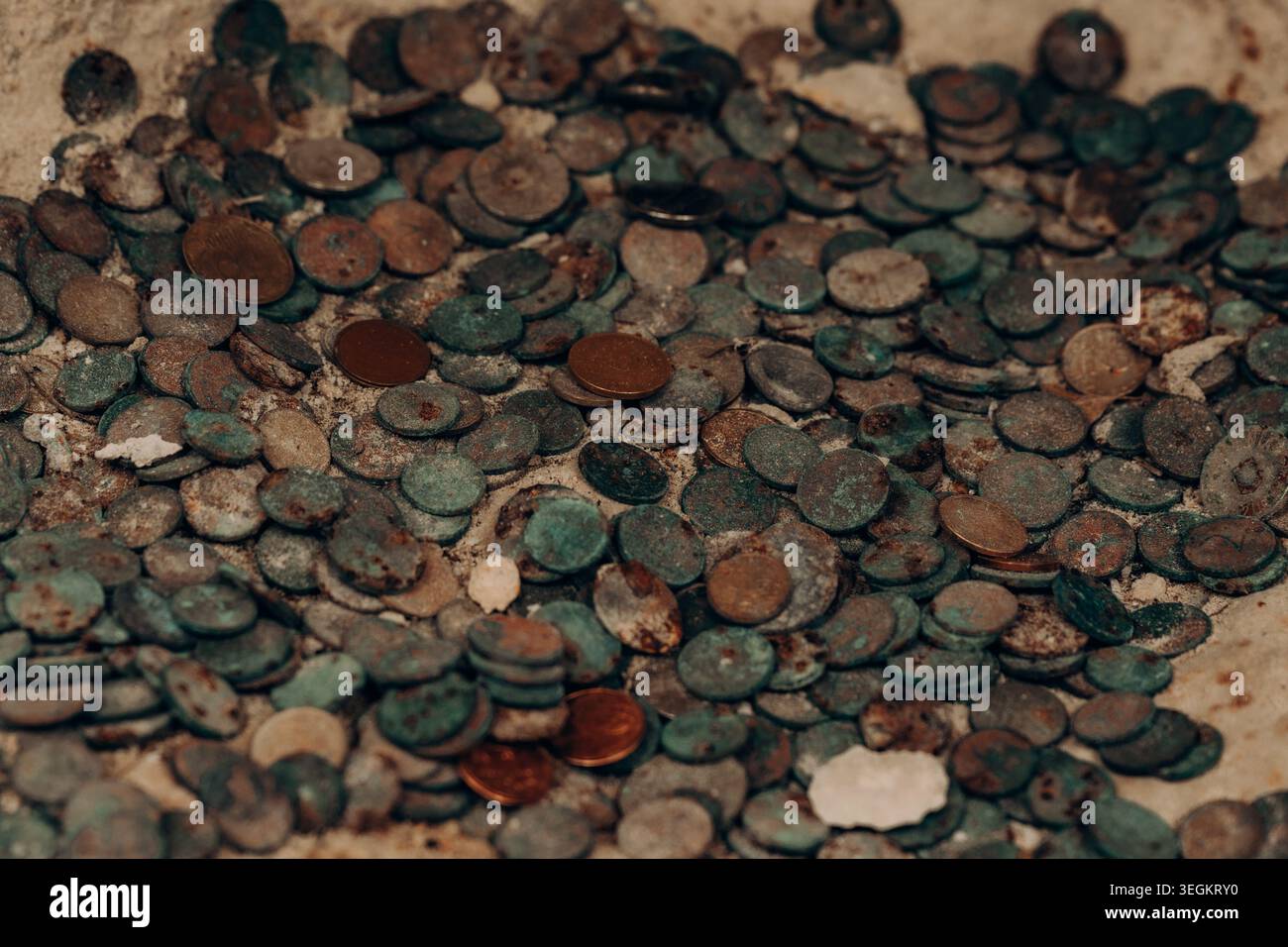 Vecchie monete ossidate sparse su una superficie in pietra usurata con patina di rame verde tonalità ruggine dettaglio storico della donazione luogo sacro texture patrimonio culturale Foto Stock