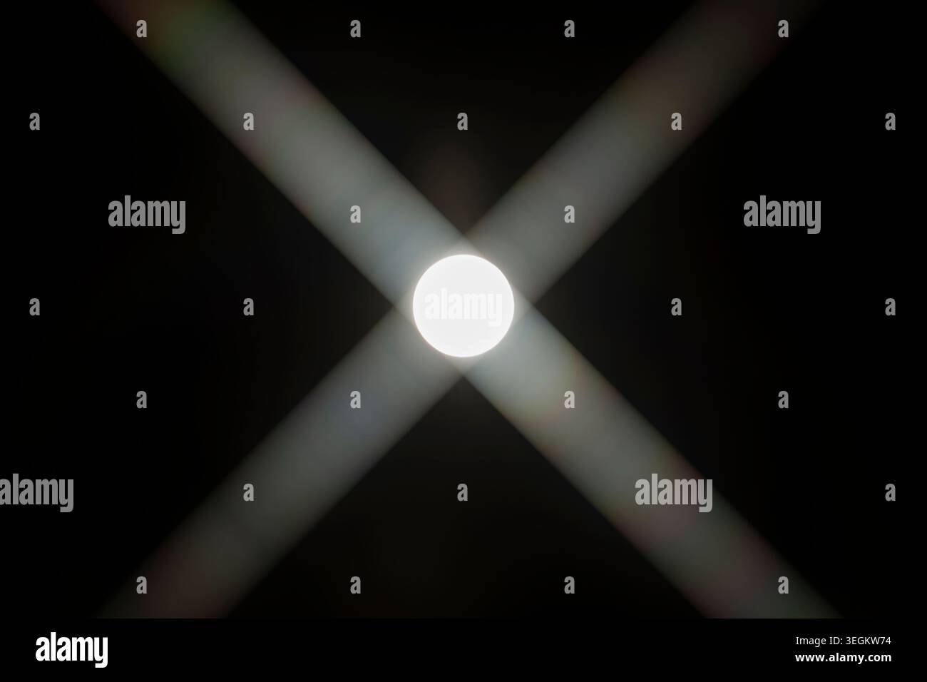 Il sole con la forma di "X" svetta contro il cielo nero Foto Stock