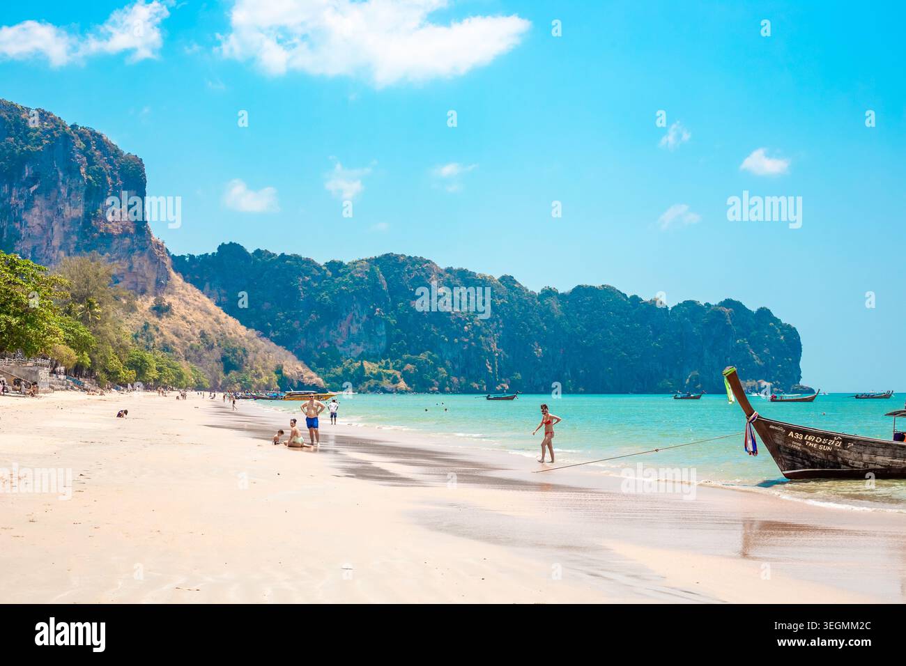 Vista panoramica di una spiaggia tropicale con sabbia bianca, acque turchesi, isole calcaree e barche a coda lunga, con gente rilassante resort balneare, tropica Foto Stock
