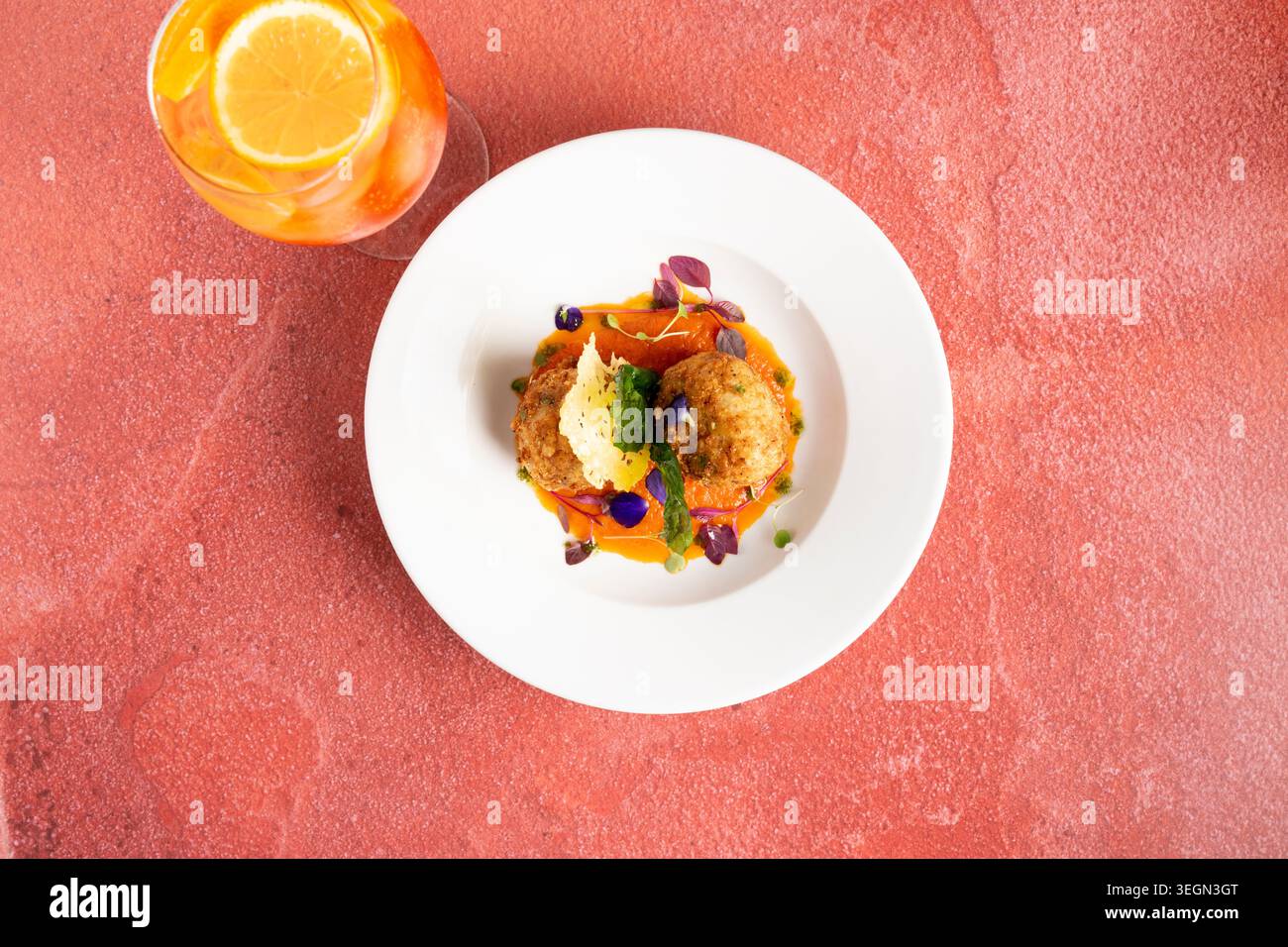 Delizioso piatto gourmet servito con vivace cocktail presso un elegante tavolo da pranzo Foto Stock