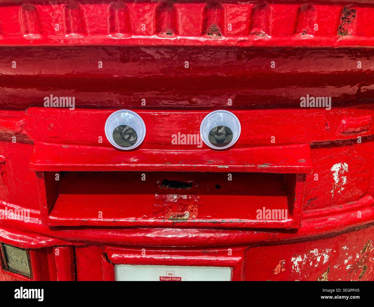 Un'immagine divertente che mostra un primo piano di un vecchio, rosso, reale posta, pilastro trasformato in un volto, con occhi e bocca - Immagine stock catturata con smartphone