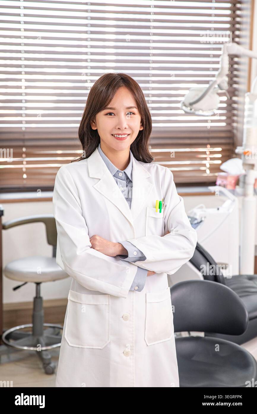 Un dentista sorridente che indossa un camice da laboratorio bianco e si trova in una moderna clinica odontoiatrica. Foto Stock