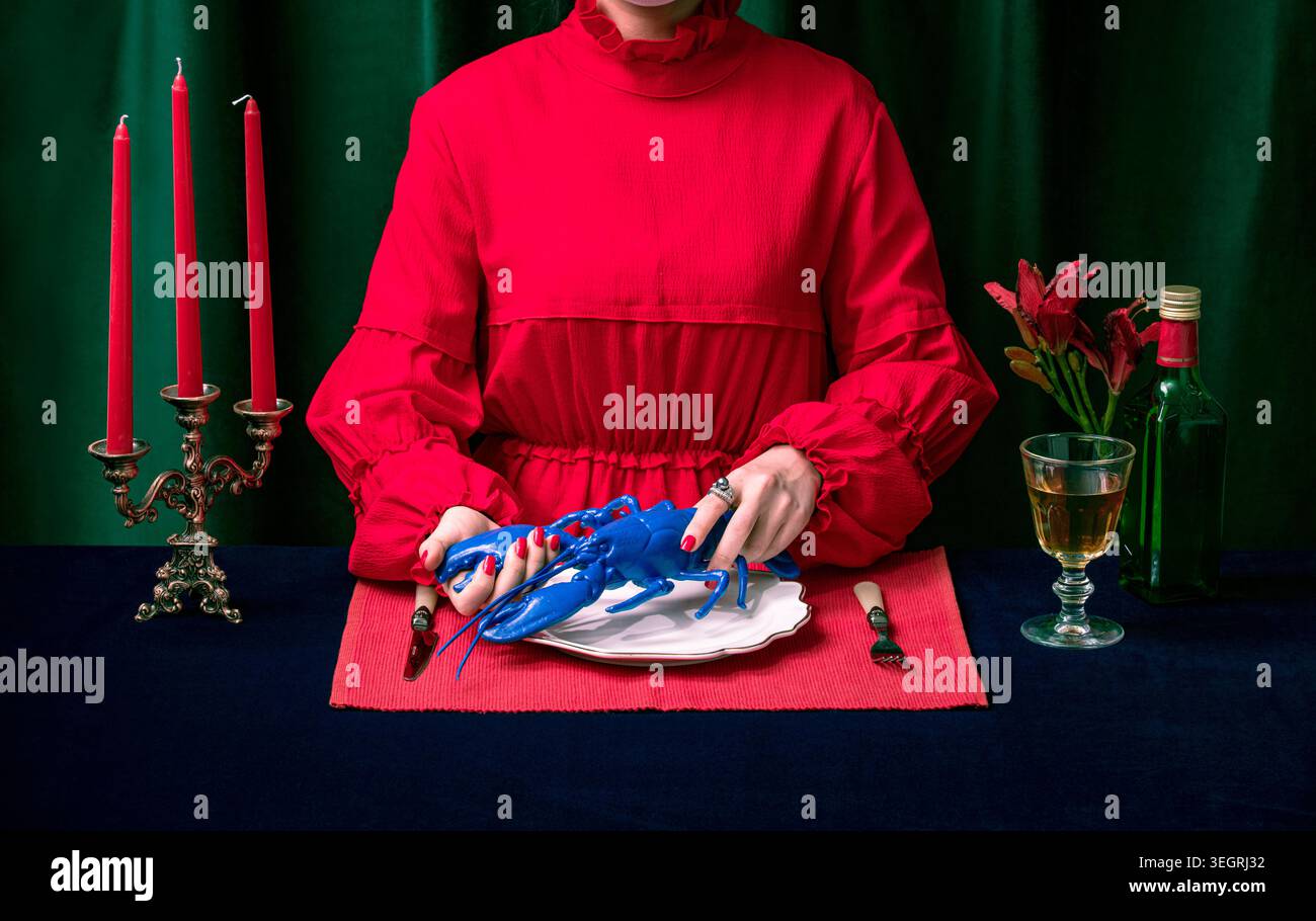 Una donna con un abito rosso tiene un'aragosta blu su un piatto bianco a un tavolo da cena formale. Foto Stock