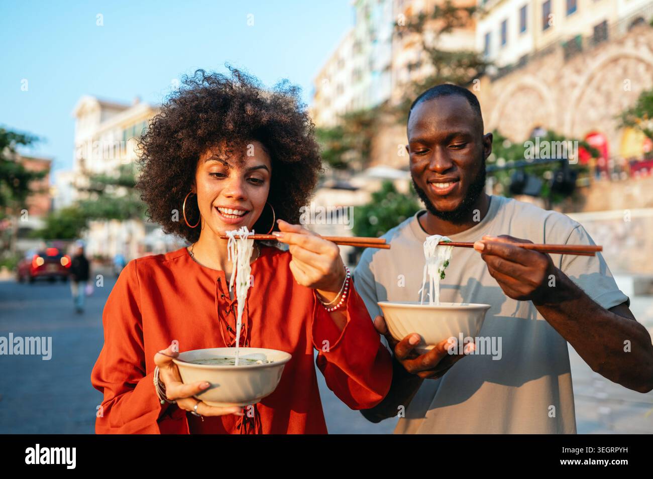 Giovani viaggiatori che si rilassano con l'autentico cibo di strada, scoprendo nuove culture e la cucina locale Foto Stock