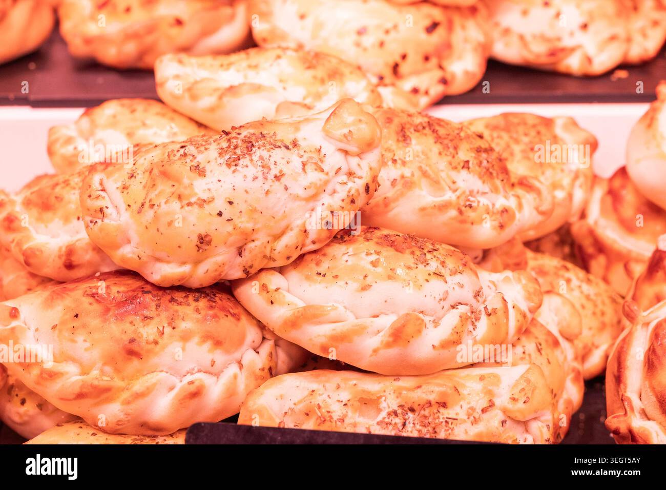 Primo piano di un mucchio di empanidas spagnole tradizionali e dorate appena sfornate o salate di pasticceria con crosta dorata al famoso la Boqueria publi Foto Stock