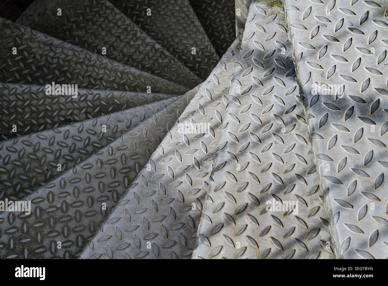 I gradini di una vecchia scala a spirale in metallo scompaiono al buio Foto Stock