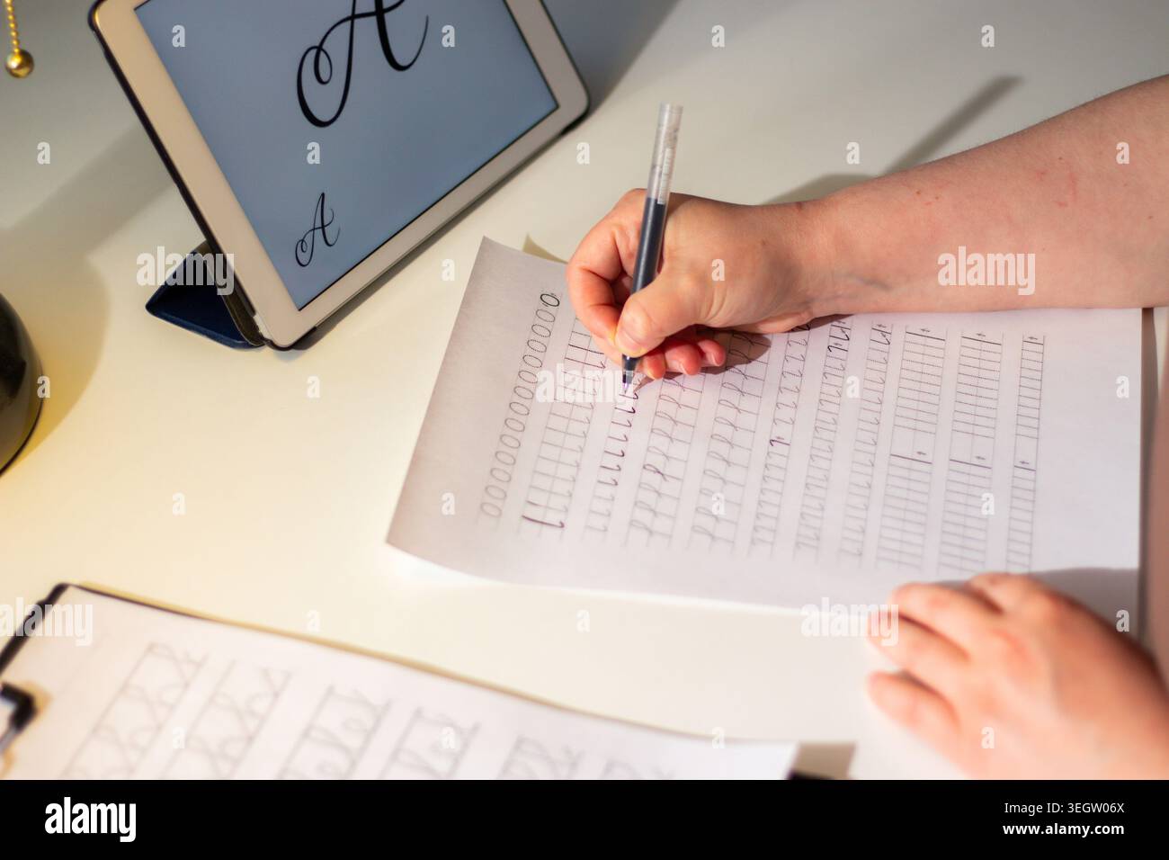 La persona seduta alla scrivania si è concentrata molto sulla scrittura su un notebook. Coinvolgimento fisico di abilità motorie scrittura a mano come allenamento cerebrale. Prevenzione dell'età rela Foto Stock