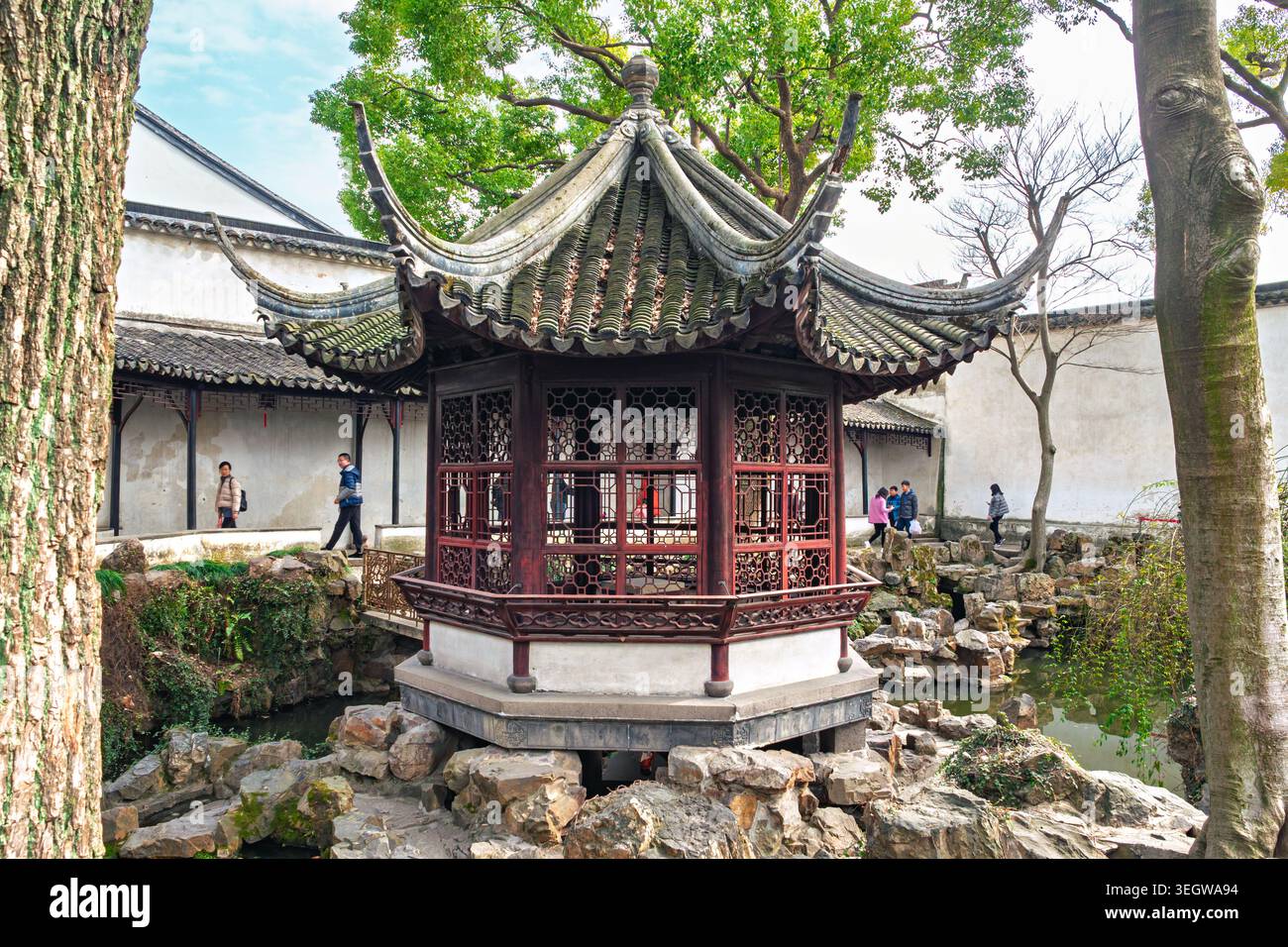Suzhou, Cina - 14 febbraio 2018: I visitatori camminano in un tradizionale padiglione cinese in un giardino a Suzhou durante un pomeriggio di sole Foto Stock