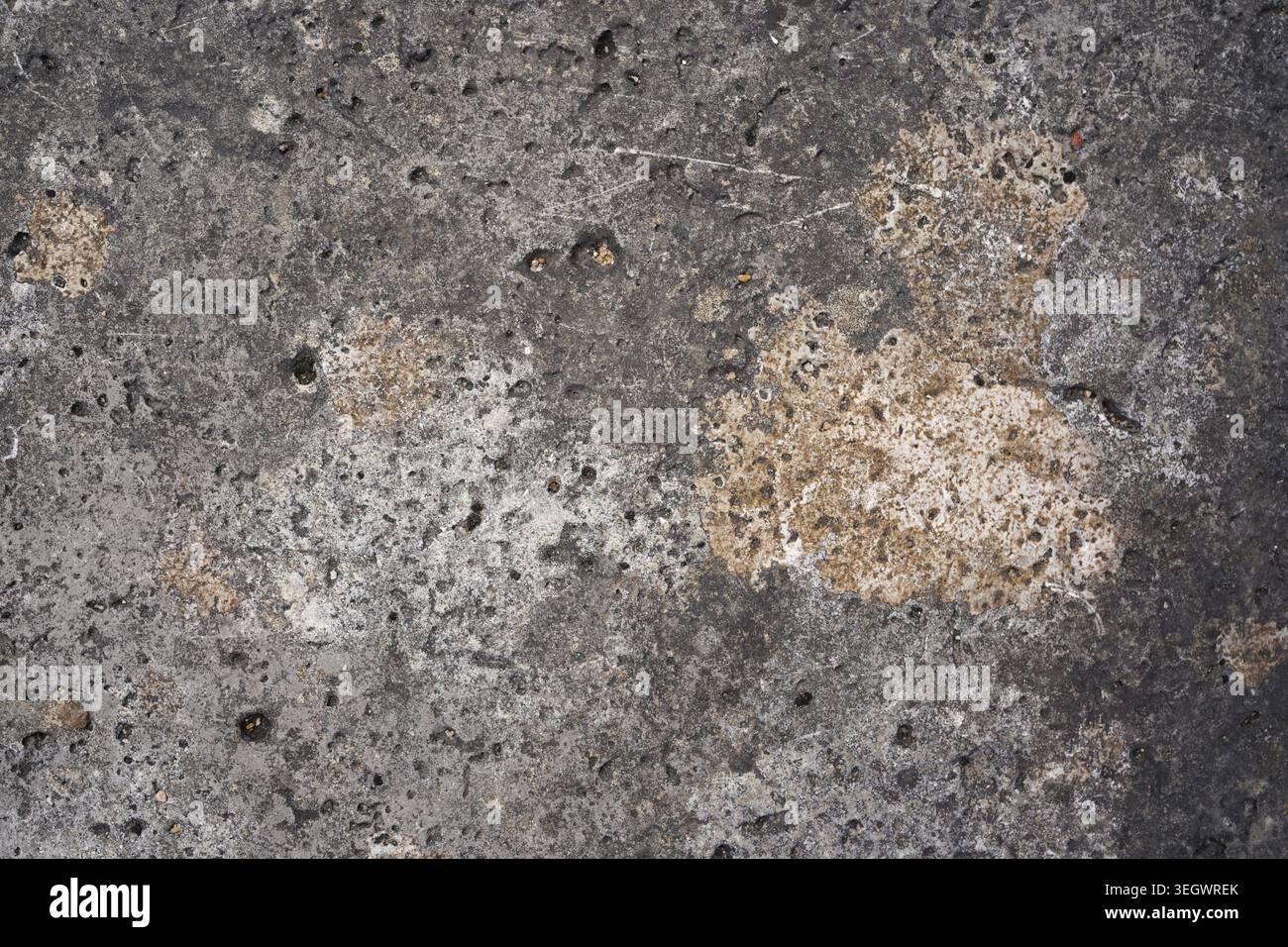 Struttura in cemento scuro resistente agli agenti atmosferici con macchie beige, graffi e fori porosi Foto Stock