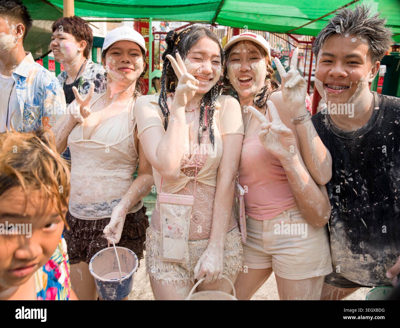 Gruppo di giovani ricoperti di pasta bianca che si godono il festival di Songkran a Lampang, Thailandia. Foto Stock
