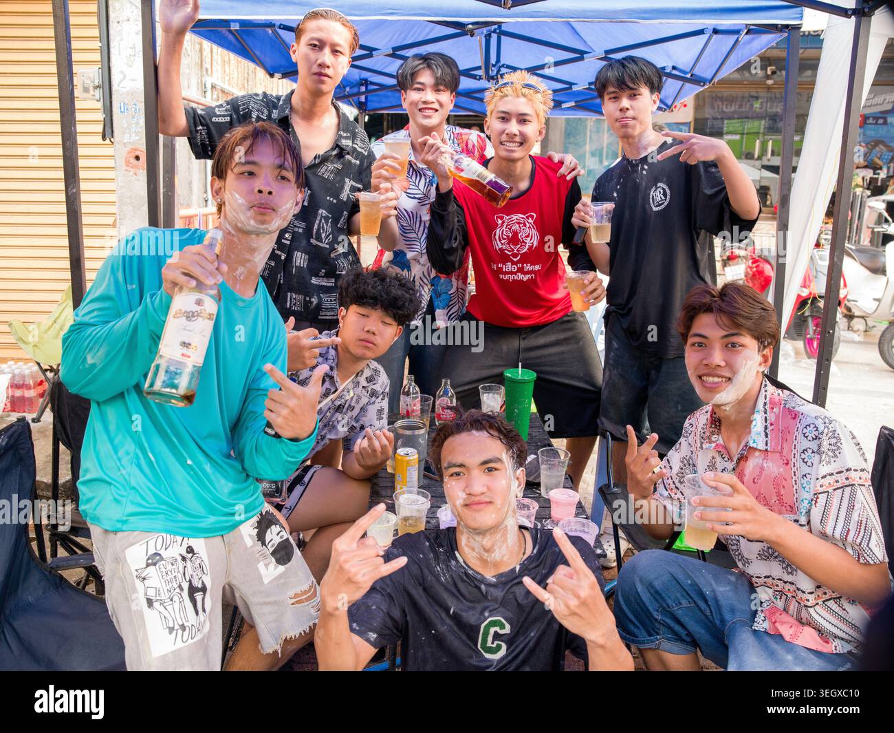 Gruppo di giovani che si divertono al festival di Songkran a Lampang, Thailandia, sorseggiando un drink e sorridendo con spirito festivo. Foto Stock