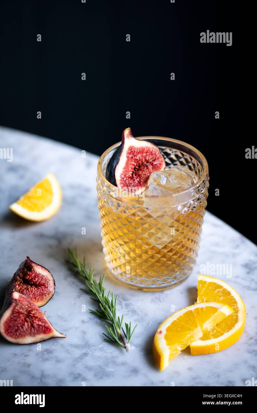 Bevanda rinfrescante con fichi e agrumi su un elegante tavolo in marmo in un ambiente accogliente Foto Stock
