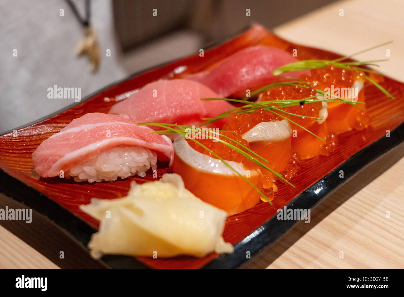 Un elegante piatto di sushi nigiri con tonno, salmone e uova, servito in un ristorante di Tokyo con guarnigione e zenzero sottaceto Foto Stock