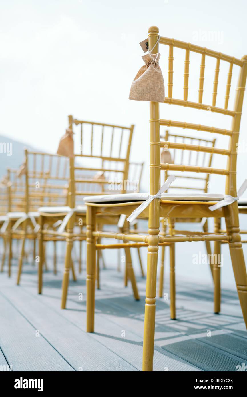 Matrimonio sul mare con posti a sedere dorati. Sedie eleganti e brezze soffici rendono ancora più suggestiva l'esperienza dei matrimoni sul mare Foto Stock