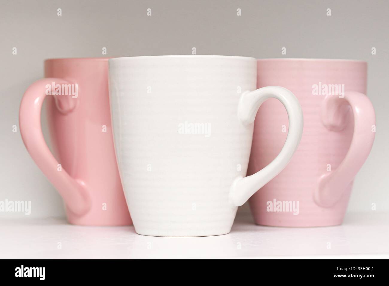 Tazze in ceramica rosa in primo piano. Stoviglie minimali da cucina e stoviglie moderne con tazze color pastello all'interno. Foto Stock