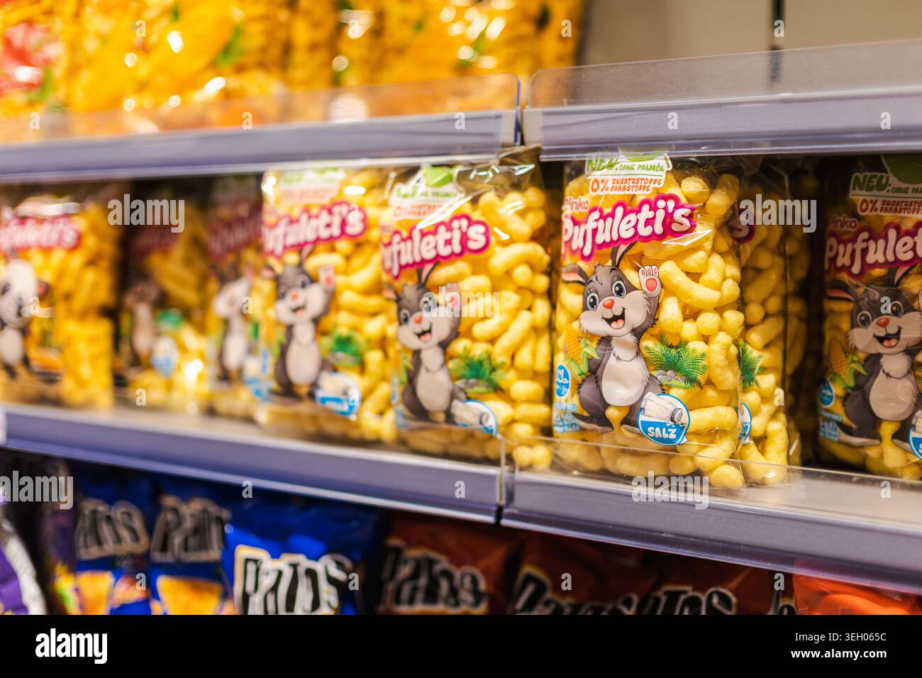 Dortmund, Germania, 6 maggio 2026: Snack di mais confezionati sullo scaffale del supermercato, colorati prodotti per bambini esposti nella corsia del supermercato Foto Stock
