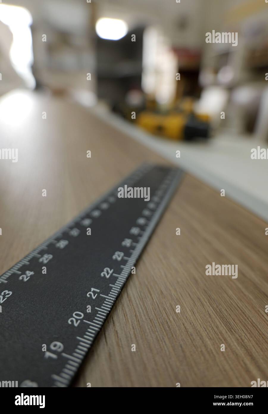 Righello in metallo su un pannello di legno che mostra misure metriche precise per la lavorazione del legno e la ristrutturazione domestica, primo piano con profondità di campo ridotta in un blurr Foto Stock