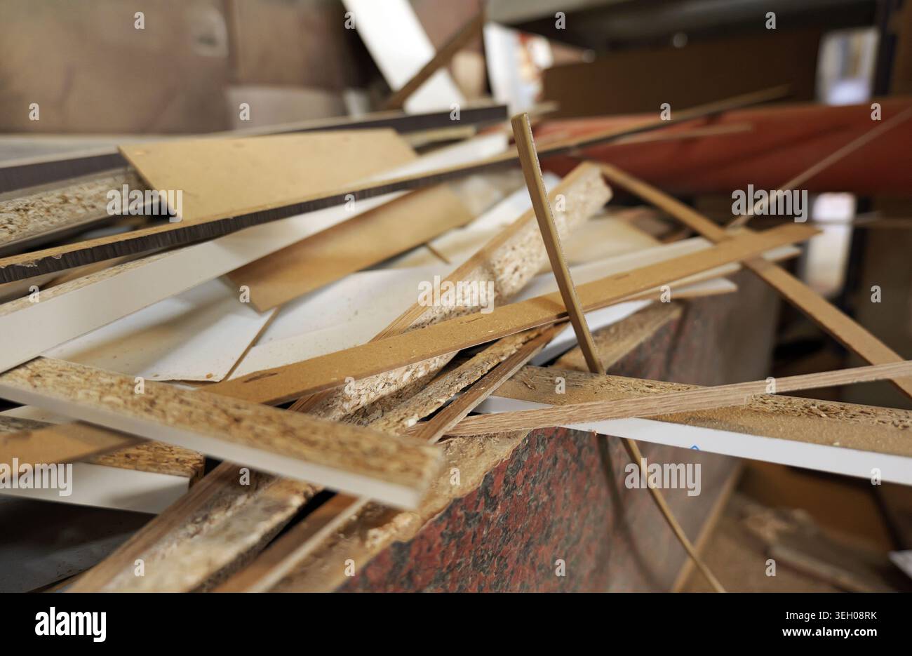 Scarti di truciolato di legno e vari pezzi di materiale che creano rifiuti e detriti, simboleggiano la produzione industriale e il processo di riciclaggio in una fabbrica Foto Stock