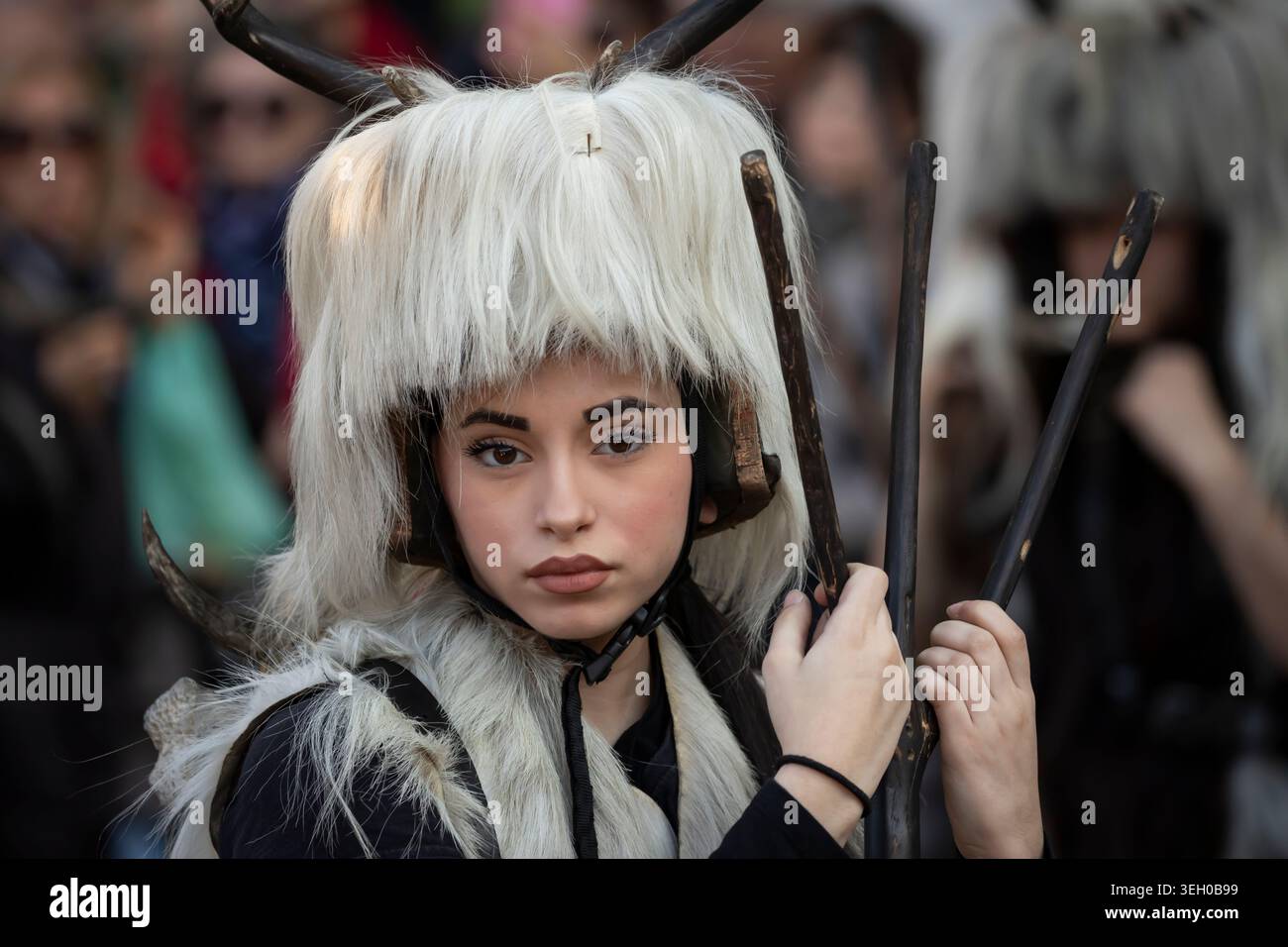 Festaiolo di Carnevale con parrucca bianca ricciolata e costume viola ornato si erge tra le folle durante il Carnevale di Venezia a Venezia, Italia, marzo 2025. Foto Stock
