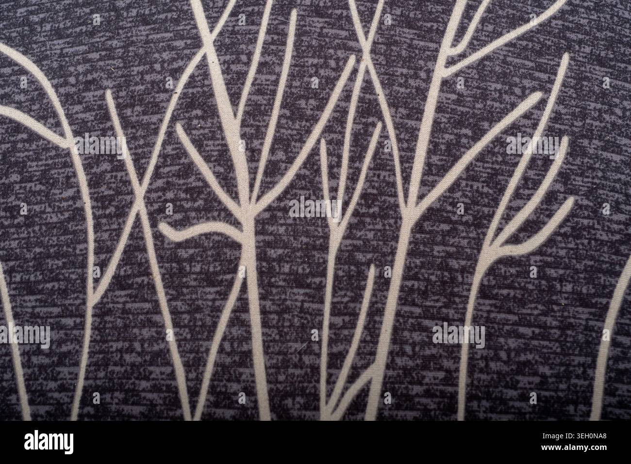 Primo piano di tessuto scuro con motivo a ramo bianco, texture tessile visibile e linee organiche decorative per sfondi di design. Foto Stock