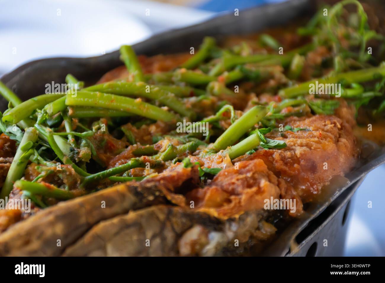 Tradizionale piatto di pesce piccante condito con verdure fresche servito caldo con ricchi condimenti e sapori saporiti con vista ravvicinata Foto Stock