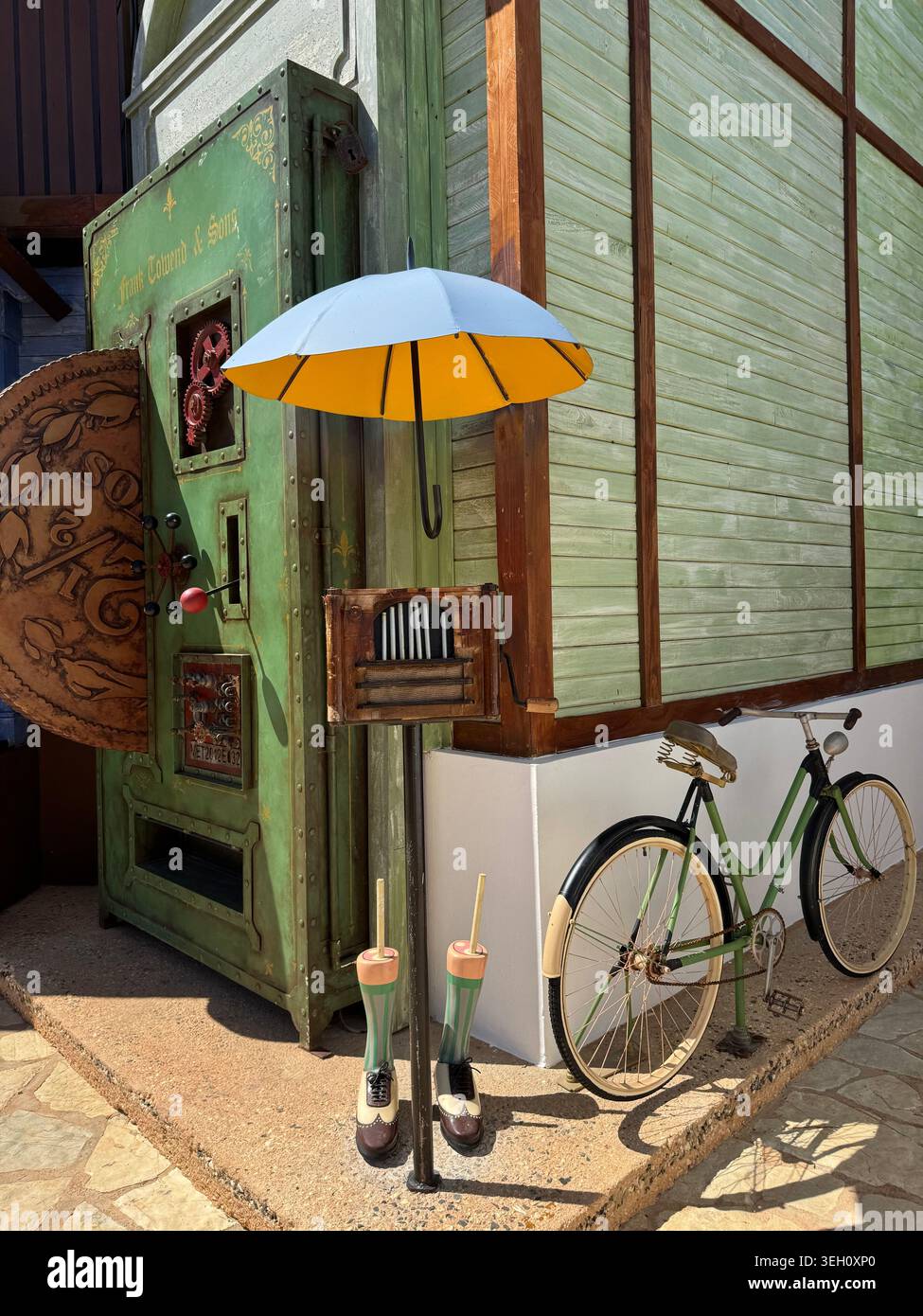 Una classica bicicletta d'epoca parcheggiata accanto a un colorato edificio in legno verde con un ombrello giallo decorativo a Cabo Rojo. - Immagine stock catturata con smartphone